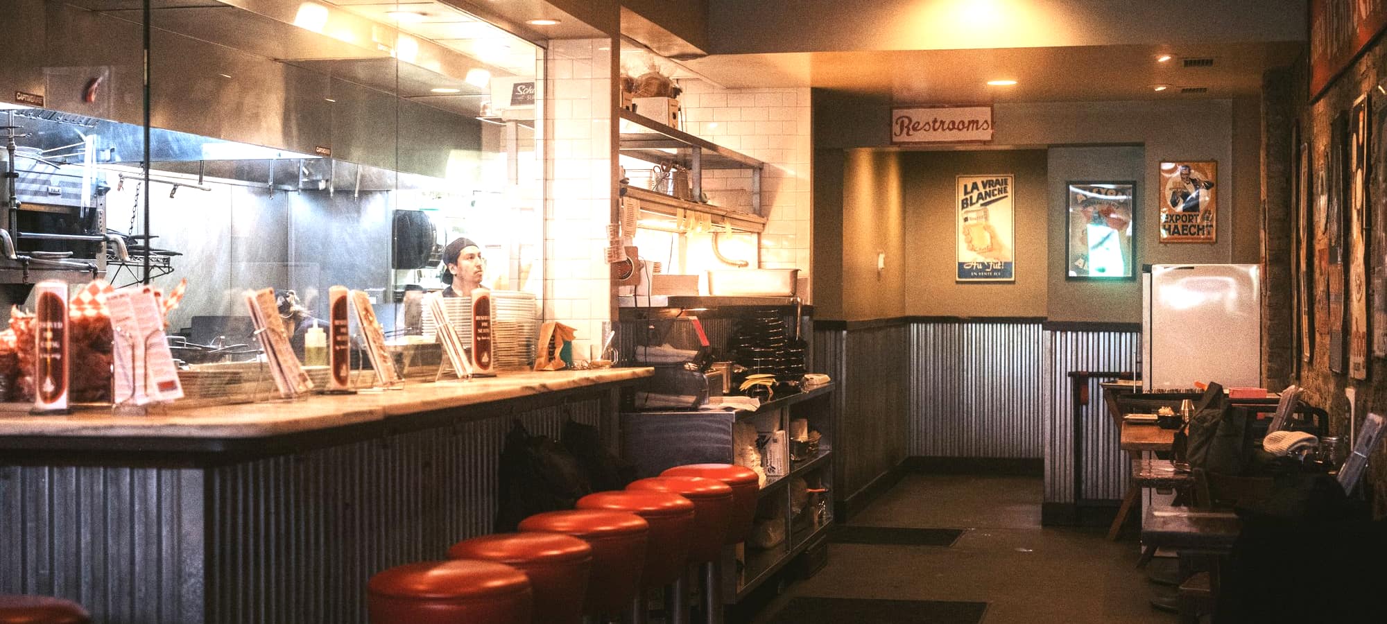 A diner counter with stools and an open kitchen behind it